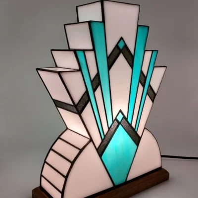 Lampe Art déco en verre coloré blanc et turquoise avec base en bois, diffusant une lumière douce.