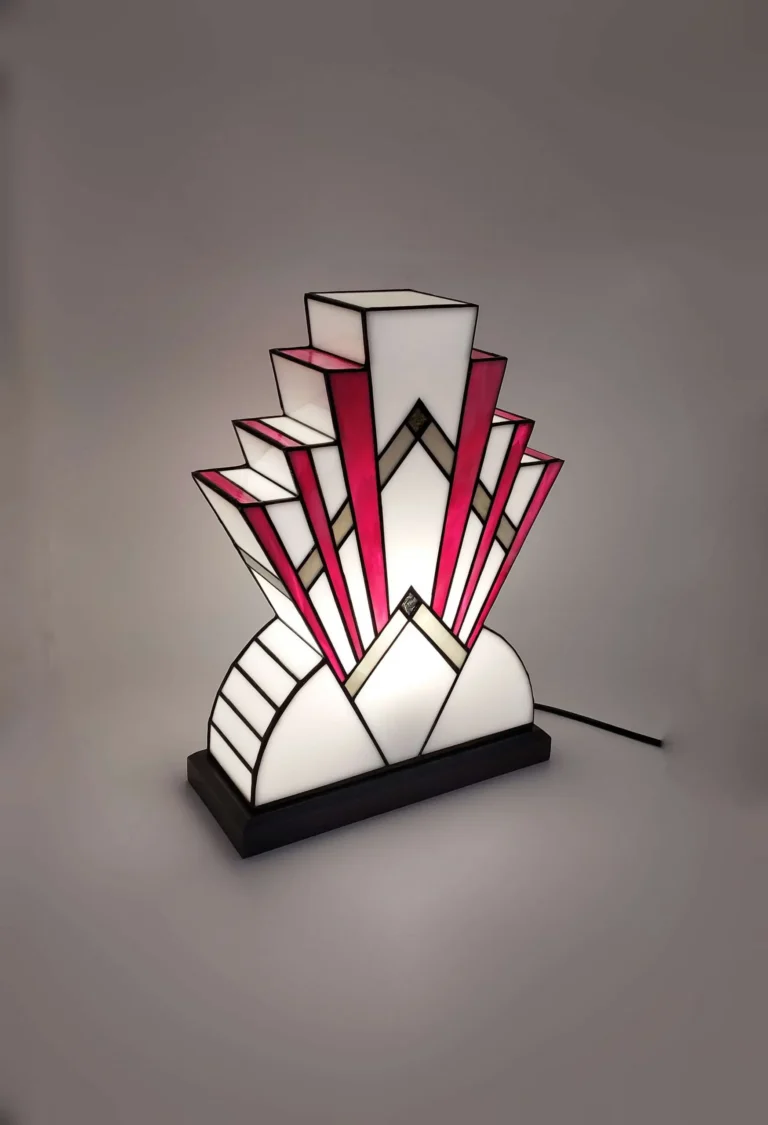 Lampe Art déco en vitrail aux formes géométriques, composée de verres opalescents blancs et rose vif avec inserts dorés, posée sur un socle en chêne massif patiné gris fer.