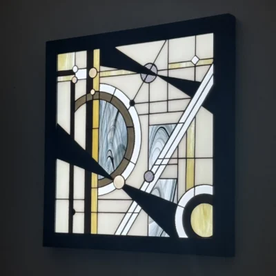 Tableau lumineux en vitrail Tiffany de style Art Déco, aux formes géométriques et verres opalescents, encadré de bois sombre et éclairé par une dalle LED.
