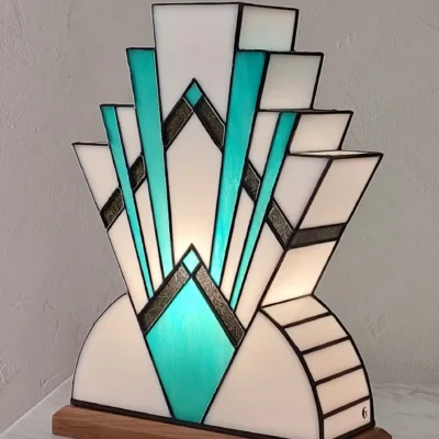 Lampe Art déco en verre coloré blanc et turquoise avec base en bois, diffusant une lumière douce.