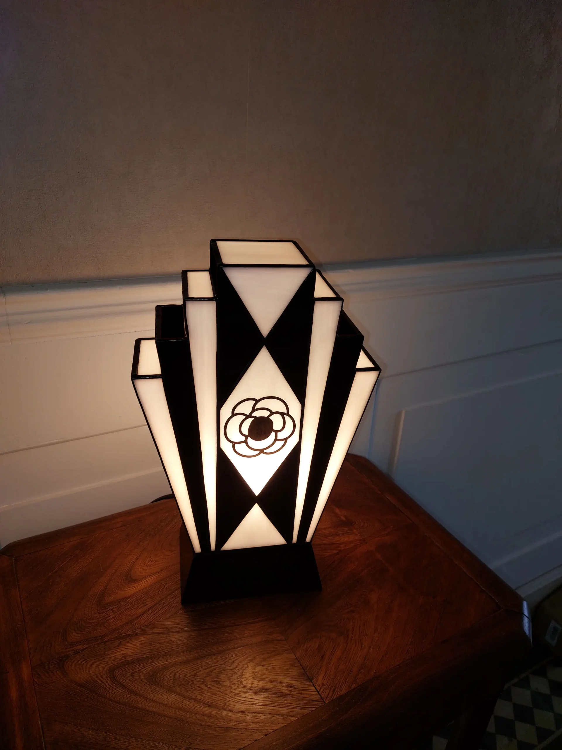 Lampe Art Déco en vitrail Tiffany noir et blanc avec motif camélia peint à la grisaille, verres opalescents et socle en chêne massif sculpté.