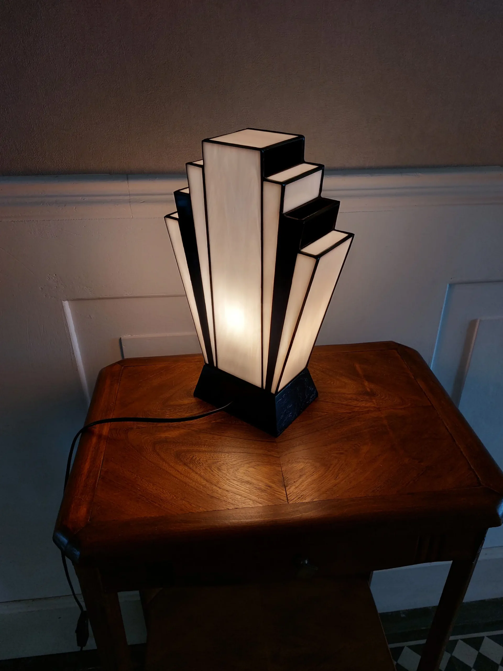 Lampe Art Déco en vitrail Tiffany noir et blanc avec motif camélia peint à la grisaille, verres opalescents et socle en chêne massif sculpté.