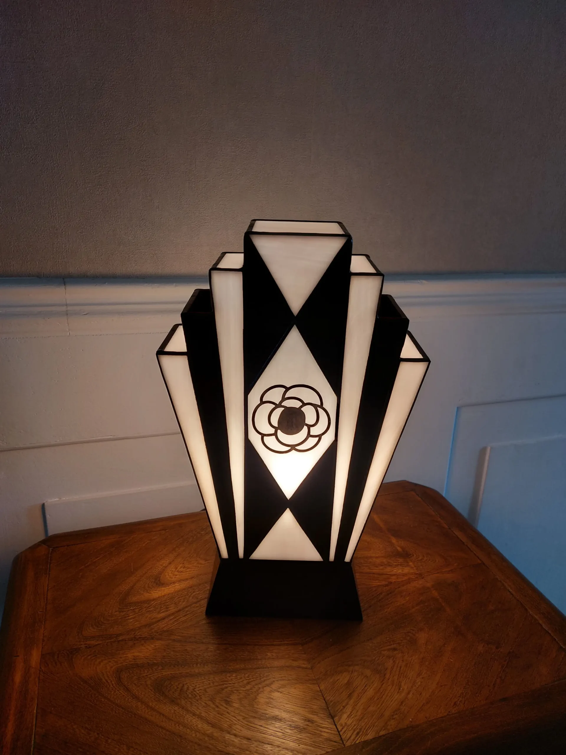 Lampe Art Déco en vitrail Tiffany noir et blanc avec motif camélia peint à la grisaille, verres opalescents et socle en chêne massif sculpté.