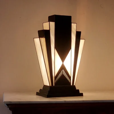 Lampe Art Déco Tiffany artisanale en verre opalescent ivoire et noir, avec touche de verre or, allumée sur socle en chêne massif sculpté.