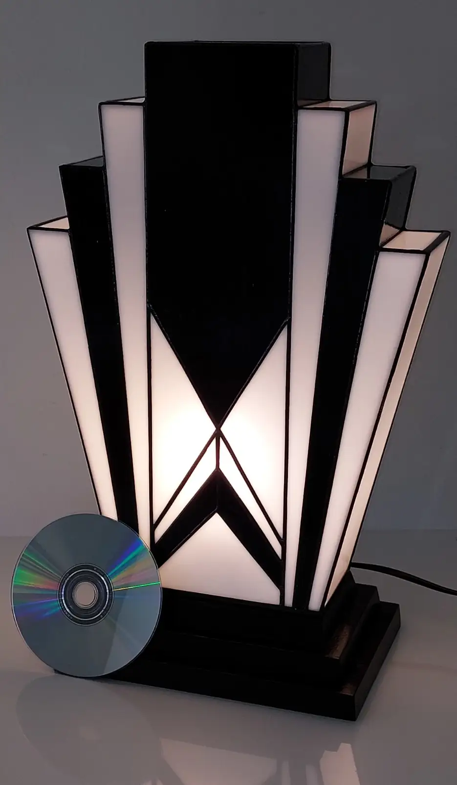 Lampe Art Déco en vitrail Tiffany noir et blanc, verres opalescents blanc perle et noir brillant, forme géométrique élancée, socle en chêne massif sculpté et teinté noir, création artisanale d’artiste verrier