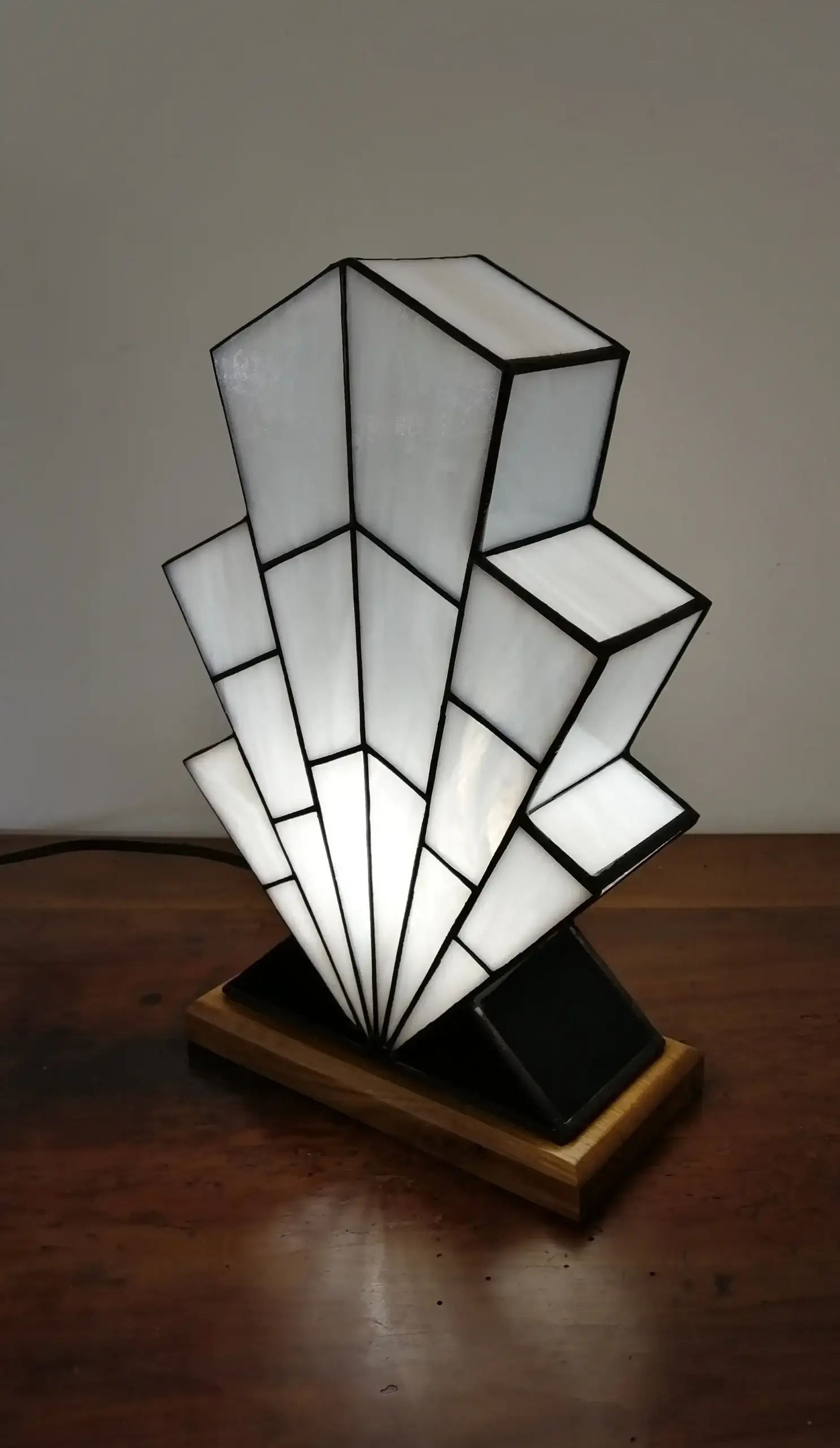 Lampe Art Déco en vitrail opalescent blanc, pied en verre noir et socle en chêne massif sculpté.