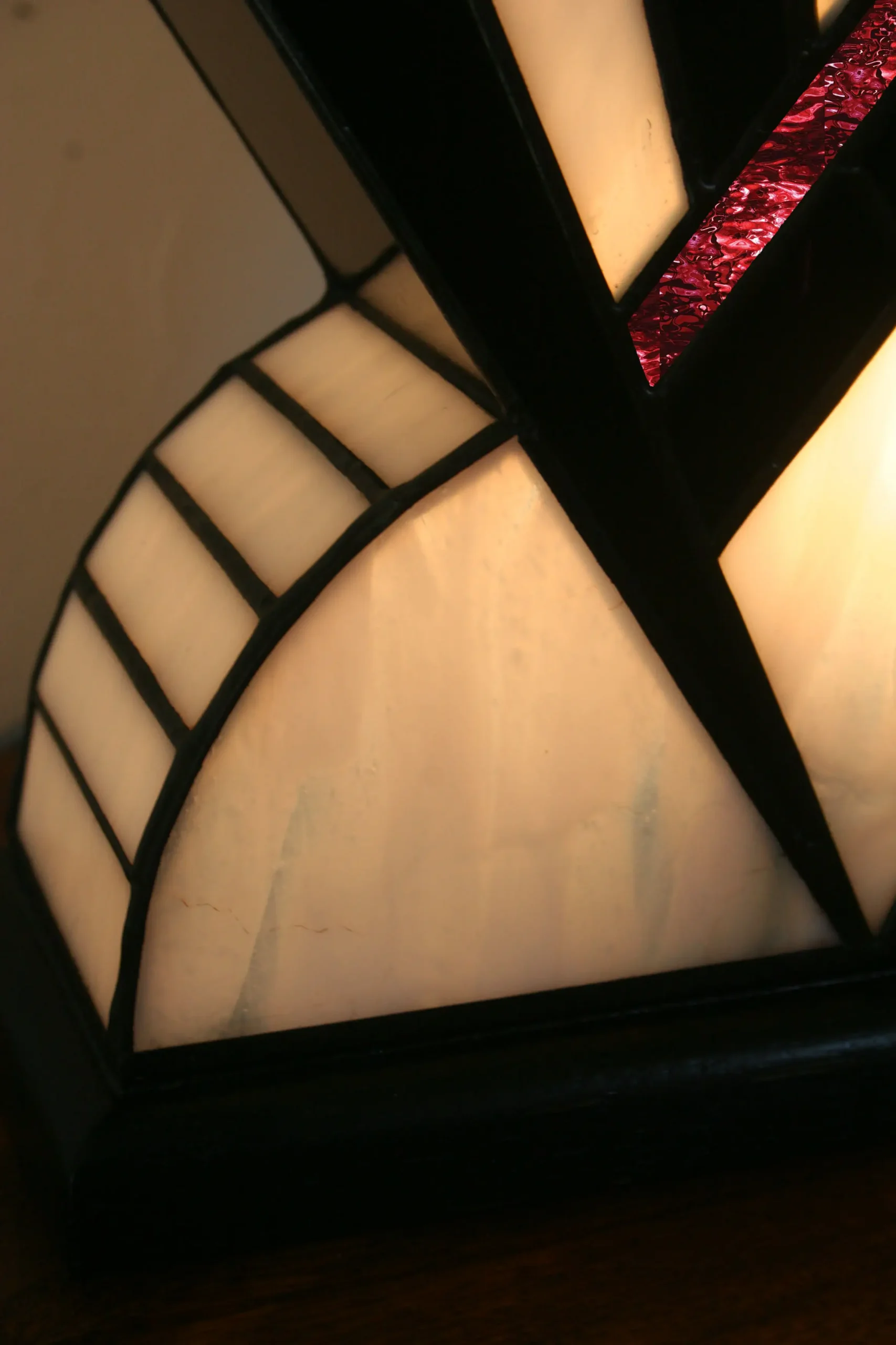Lampe Art Déco artisanale en vitrail opalescent blanc et noir laqué, avec touche de verre rouge, posée sur socle en chêne massif noir.