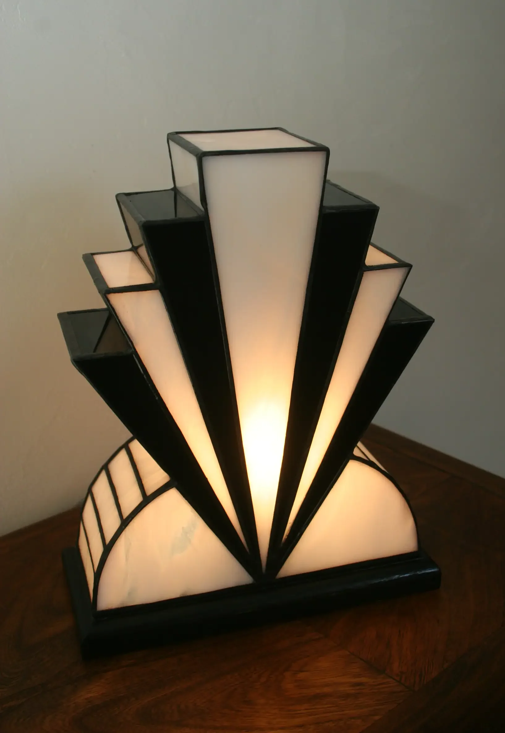Lampe Art Déco artisanale en vitrail opalescent blanc et noir laqué, avec touche de verre rouge, posée sur socle en chêne massif noir.