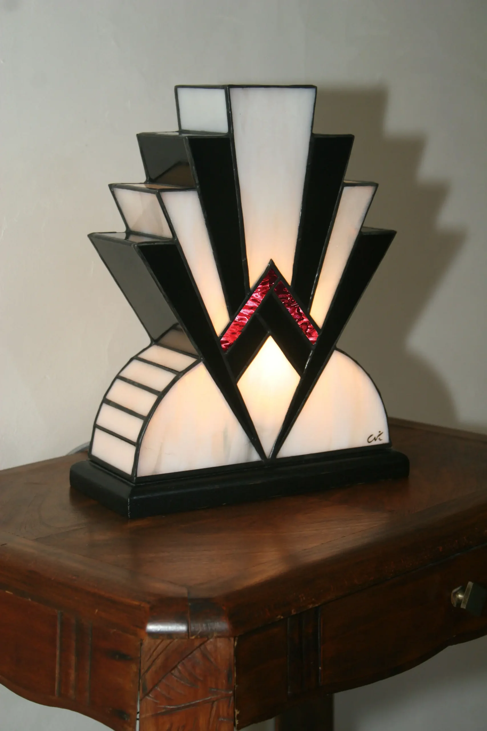 Lampe Art Déco artisanale en vitrail opalescent blanc et noir laqué, avec touche de verre rouge, posée sur socle en chêne massif noir.