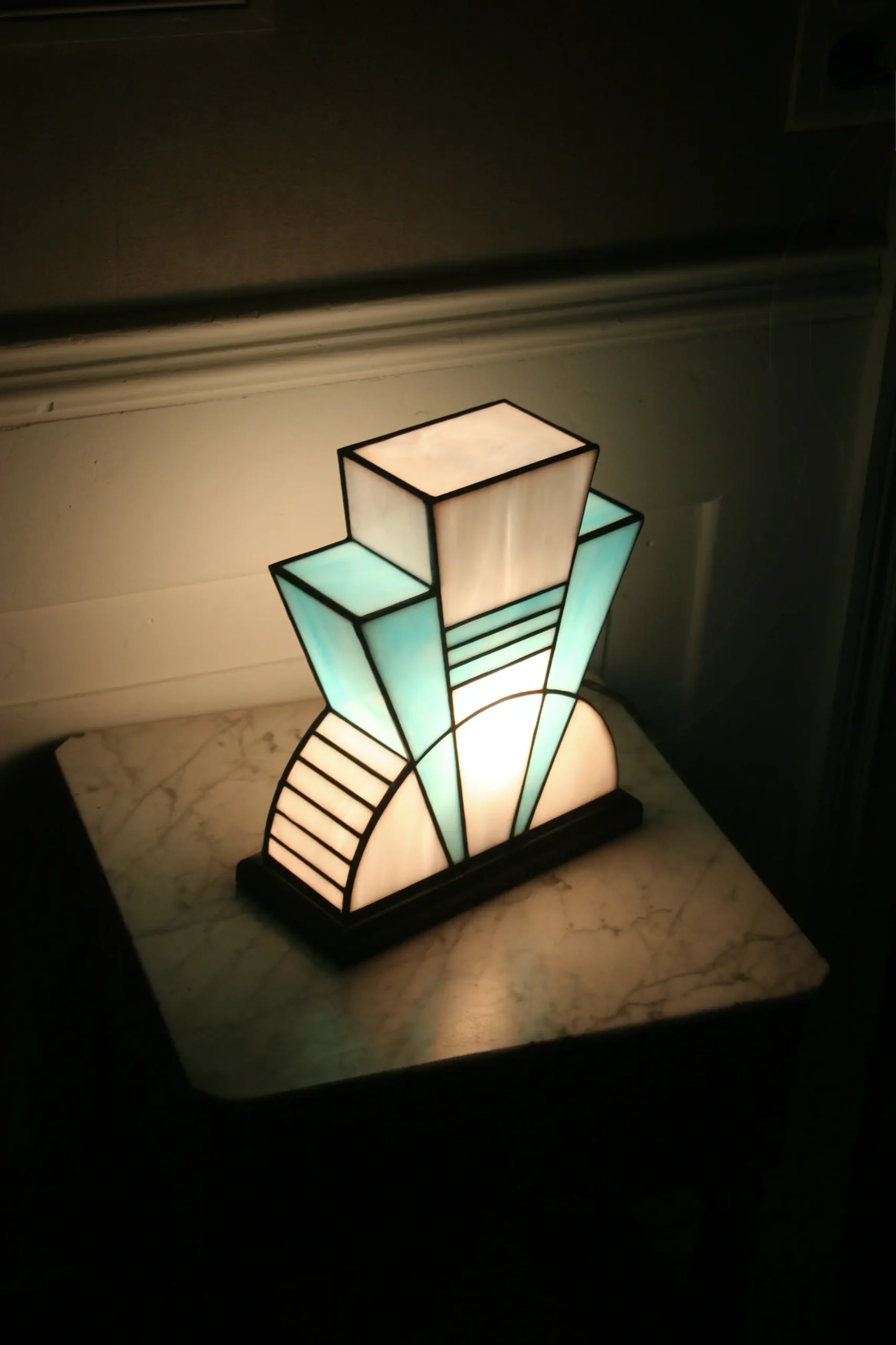 Lampe artisanale en verre opalescent blanc et bleu turquoise, finition antique, sur socle en chêne massif sculpté noir.