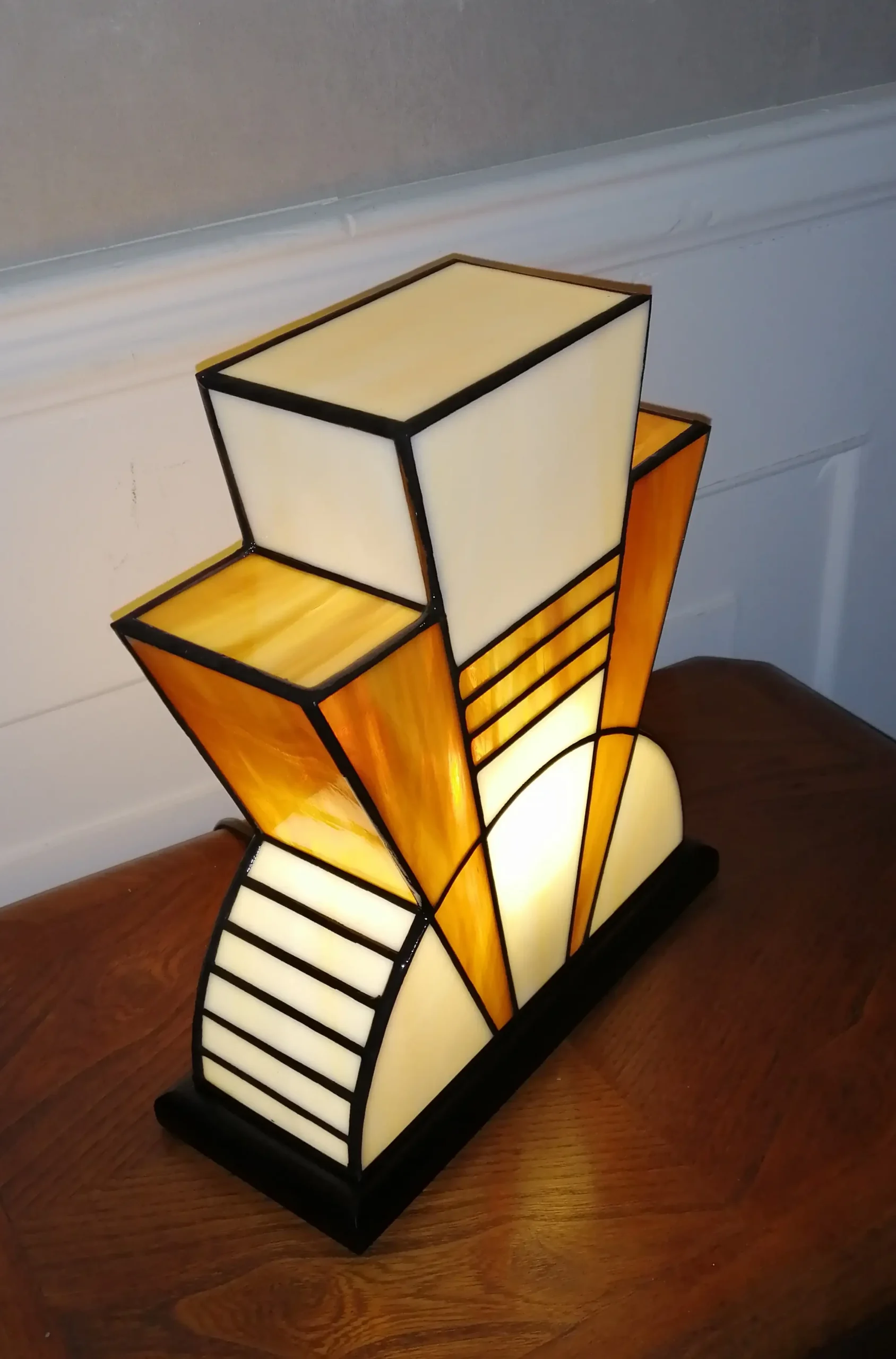 Lampe artisanale en verre opalescent ivoire strié de miel et caramel chaud, posée sur un socle en chêne massif sculpté et teinté chêne doré.