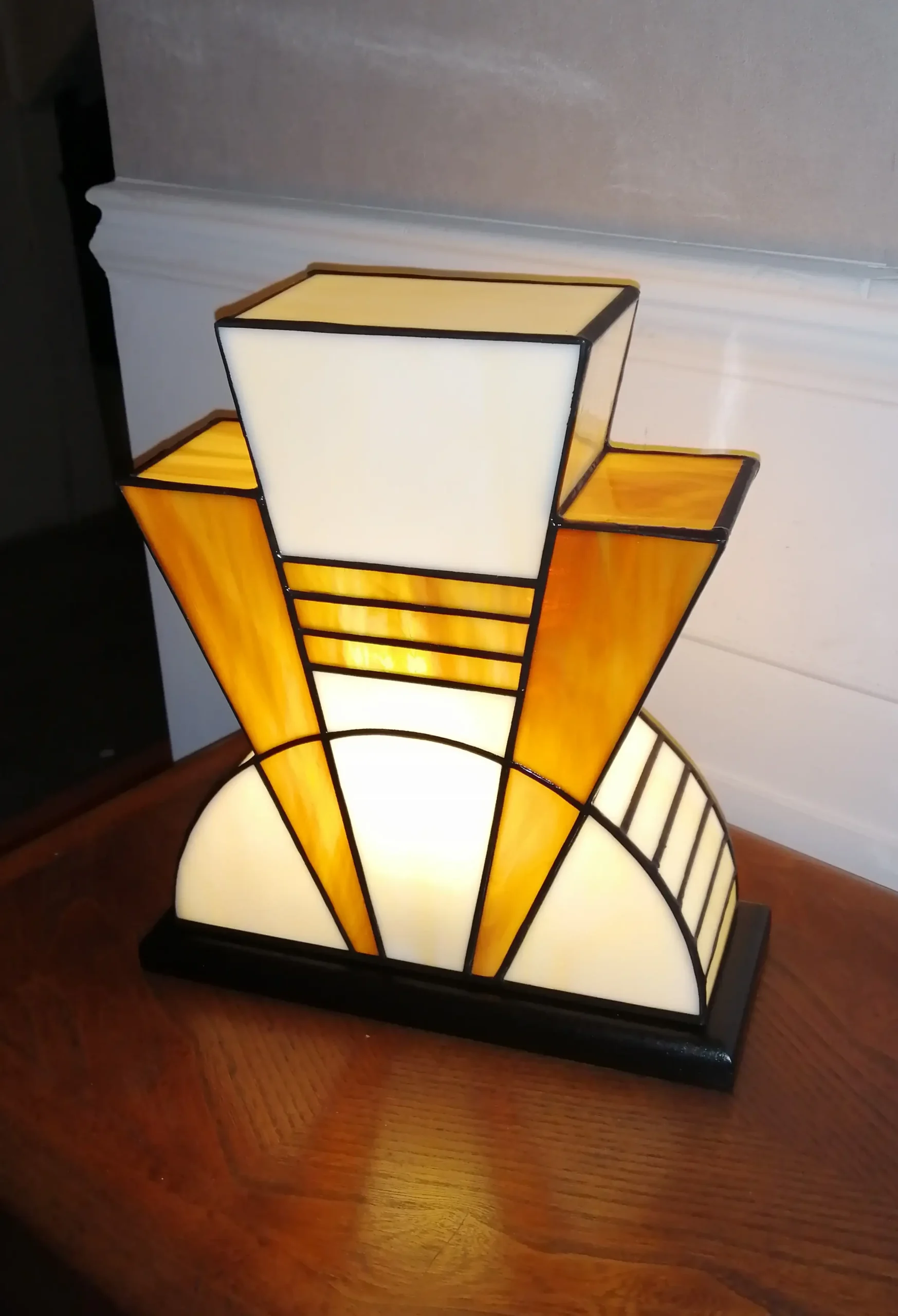 Lampe artisanale en verre opalescent ivoire strié de miel et caramel chaud, posée sur un socle en chêne massif sculpté et teinté chêne doré.