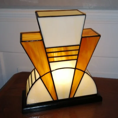 Lampe artisanale en verre opalescent ivoire strié de miel et caramel chaud, posée sur un socle en chêne massif sculpté et teinté chêne doré.