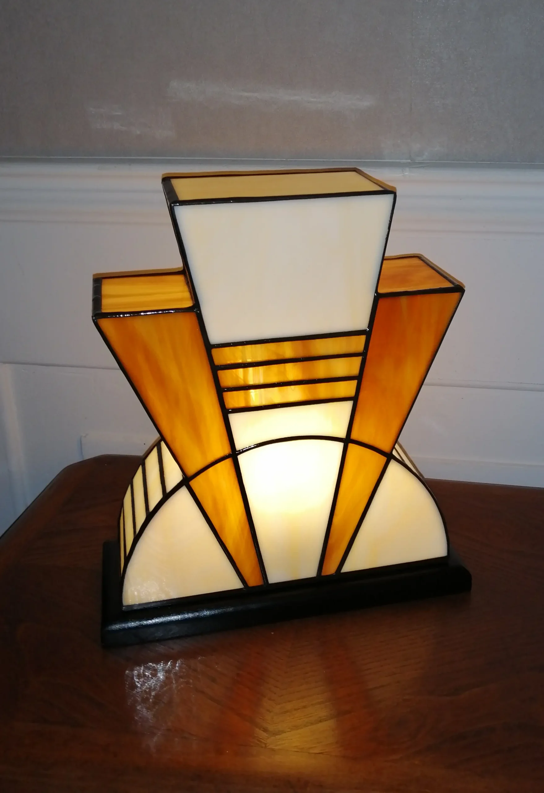 Lampe artisanale en verre opalescent ivoire strié de miel et caramel chaud, posée sur un socle en chêne massif sculpté et teinté chêne doré.