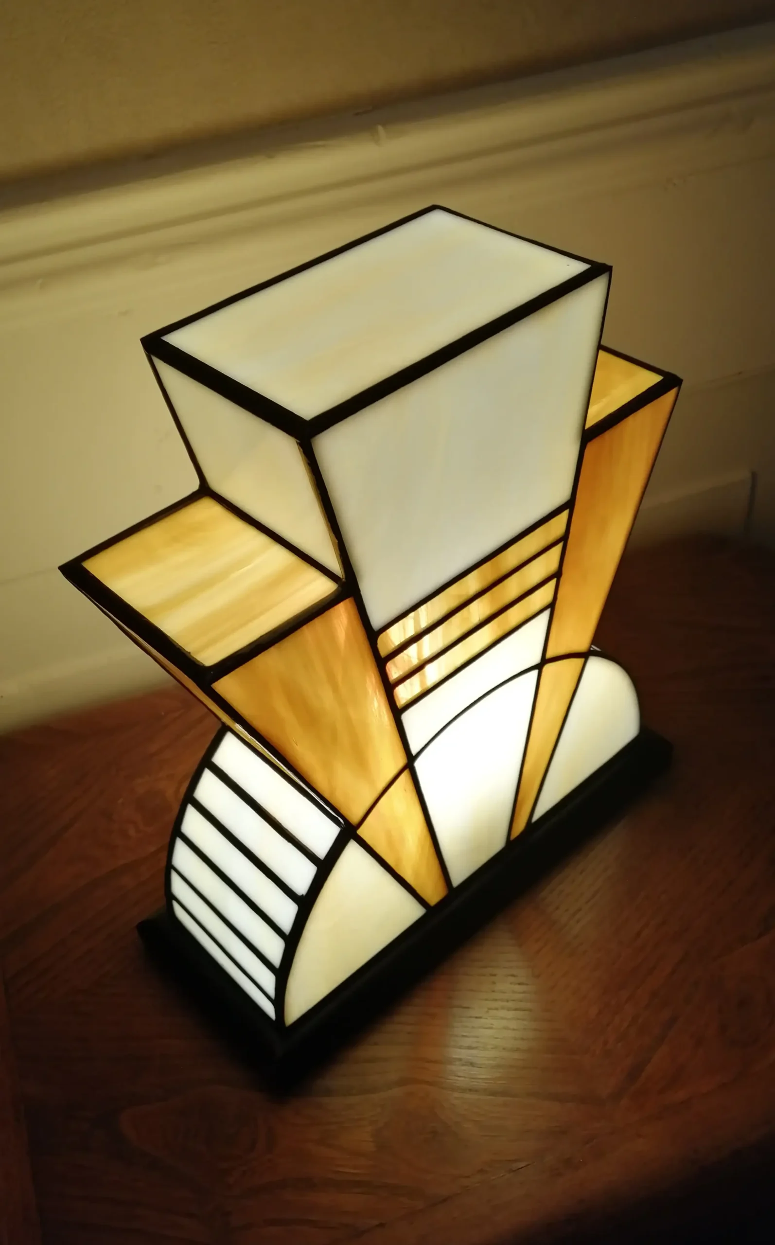 Lampe artisanale en verre opalescent ivoire strié de miel et caramel chaud, posée sur un socle en chêne massif sculpté et teinté chêne doré.