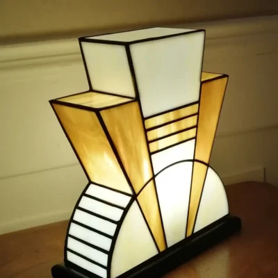 Lampe artisanale en verre opalescent ivoire strié de miel et caramel chaud, posée sur un socle en chêne massif sculpté et teinté chêne doré.