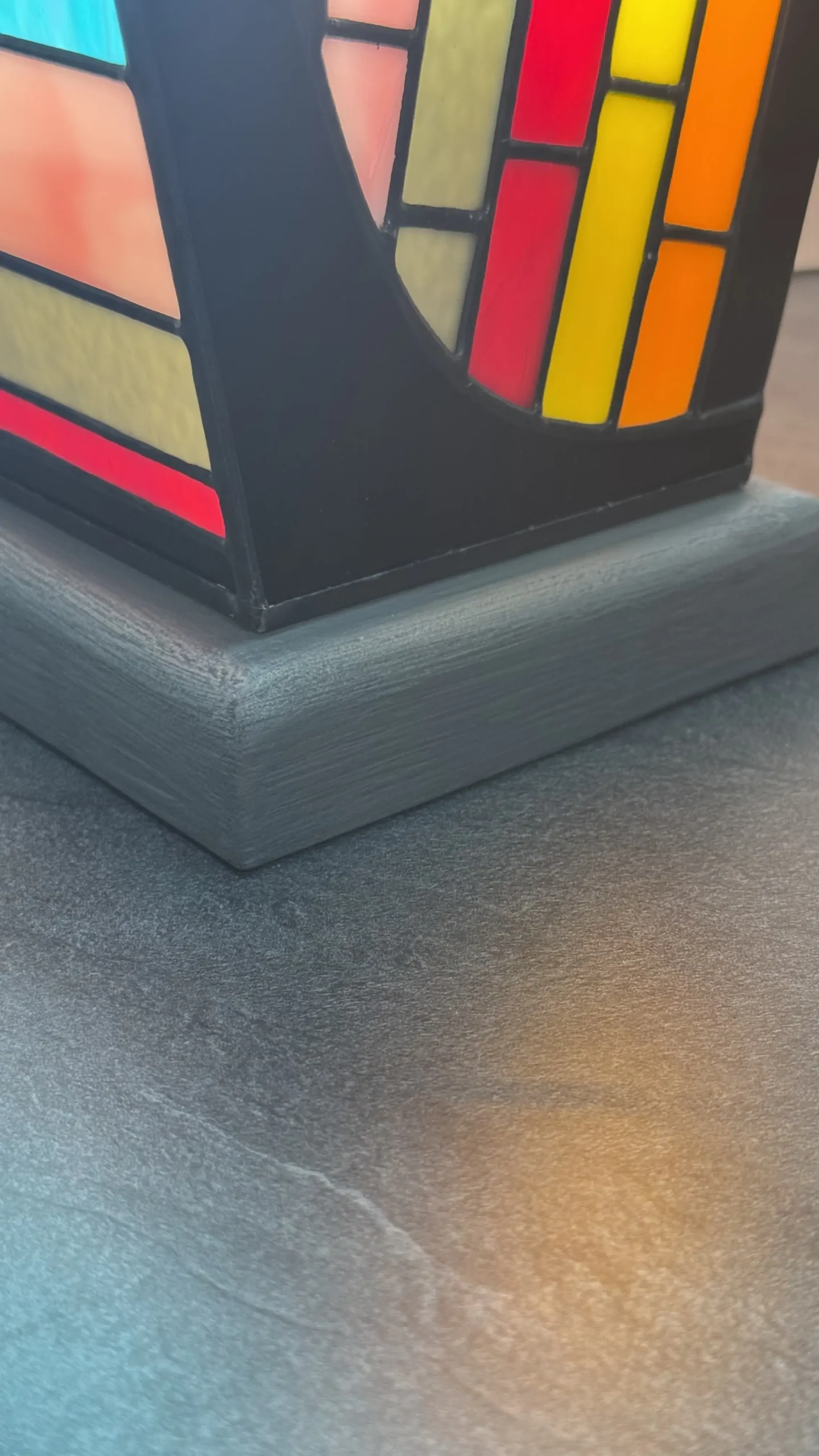 Lampe d’art contemporain Harpège Zénith en vitrail Tiffany, forme de harpe, verres opalescents multicolores sur structure noire et socle en béton ciré.