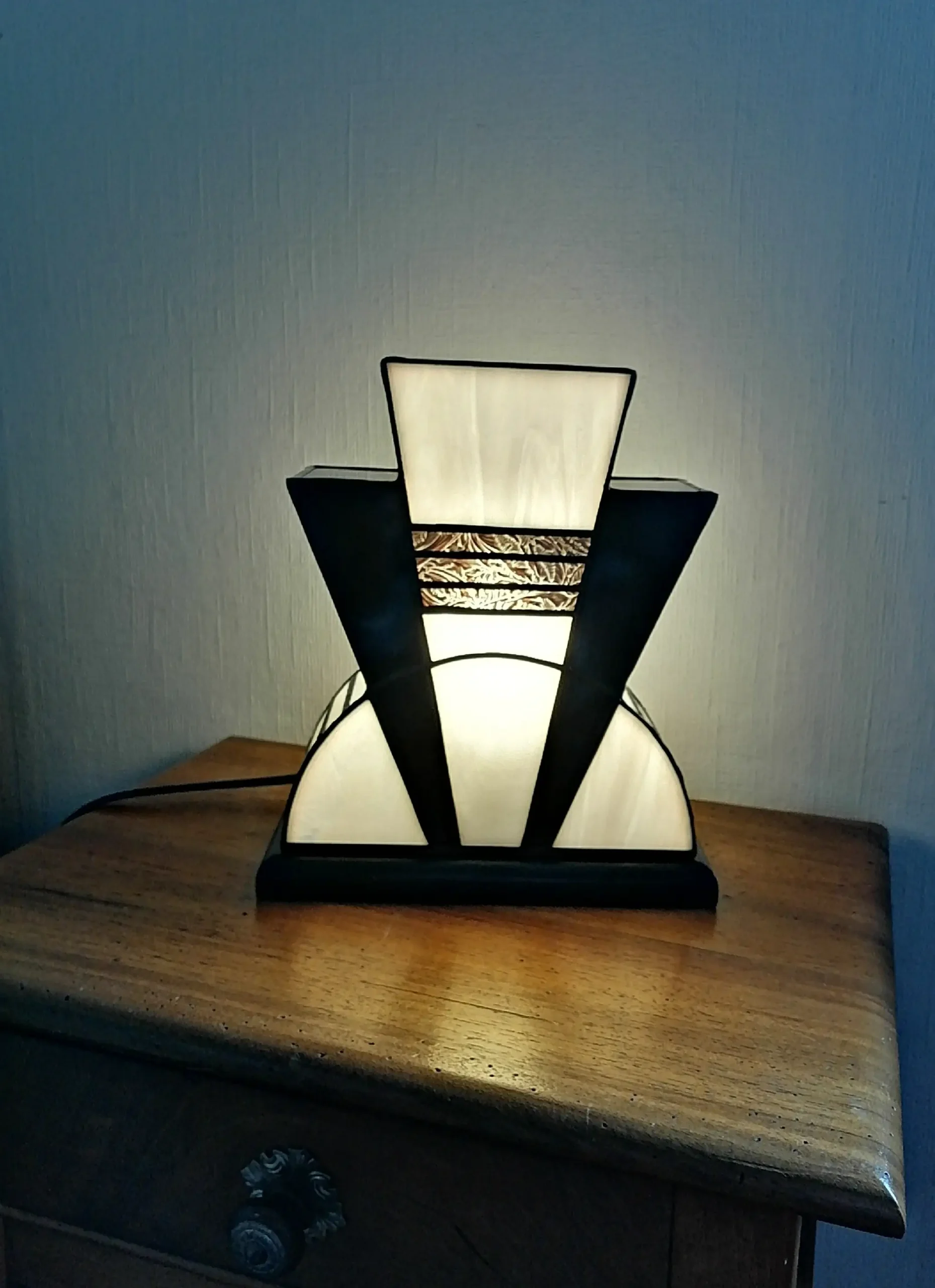 Lampe Art Déco en vitrail Tiffany blanc opalescent et noir glacé avec incrustation dorée à palmettes, socle en chêne massif noir patiné, création artisanale faite main.