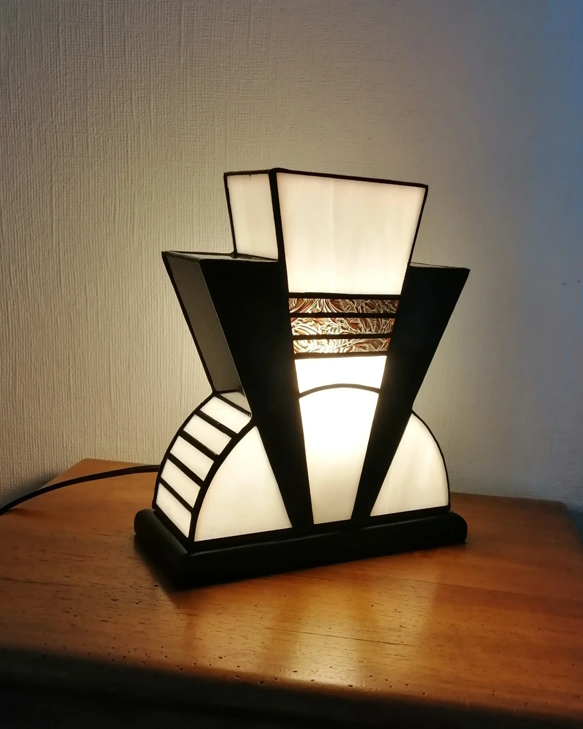 Lampe Art Déco en vitrail Tiffany blanc opalescent et noir glacé avec incrustation dorée à palmettes, socle en chêne massif noir patiné, création artisanale faite main.