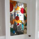 Porte intérieure blanche avec panneau en vitrail coloré abstrait, apportant lumière et élégance à une entrée lumineuse au sol damier.