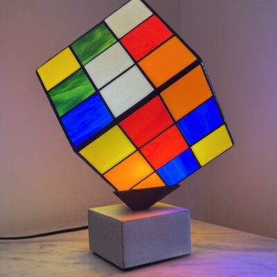 Lampe Rubik's Cube en vitrail Tiffany sur socle béton, luminaire artisanal français multicolore de style design contemporain.